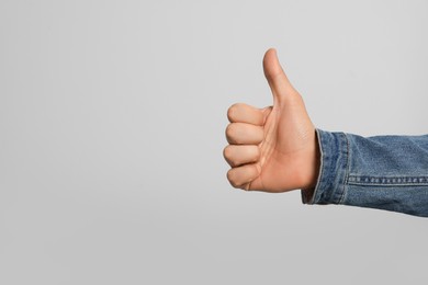 Photo of Man showing thumb up on grey background, closeup. Space for text