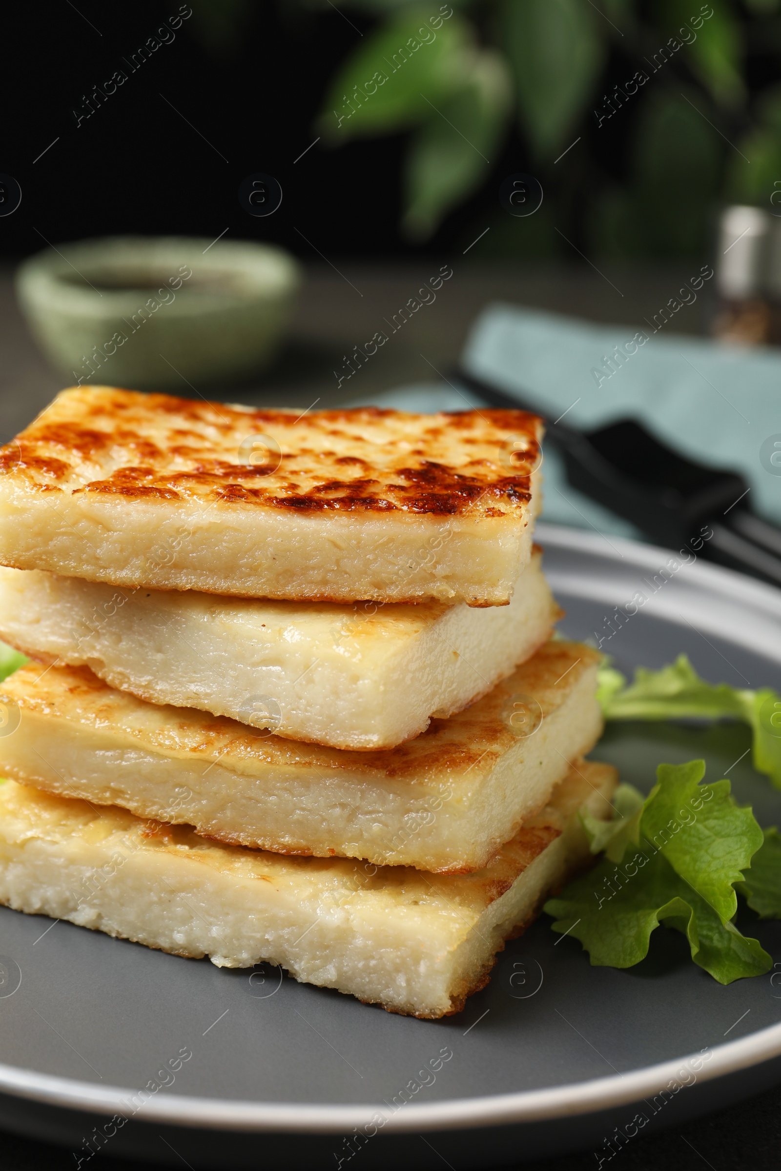Photo of Delicious turnip cake with lettuce salad served on grey plate, closeup