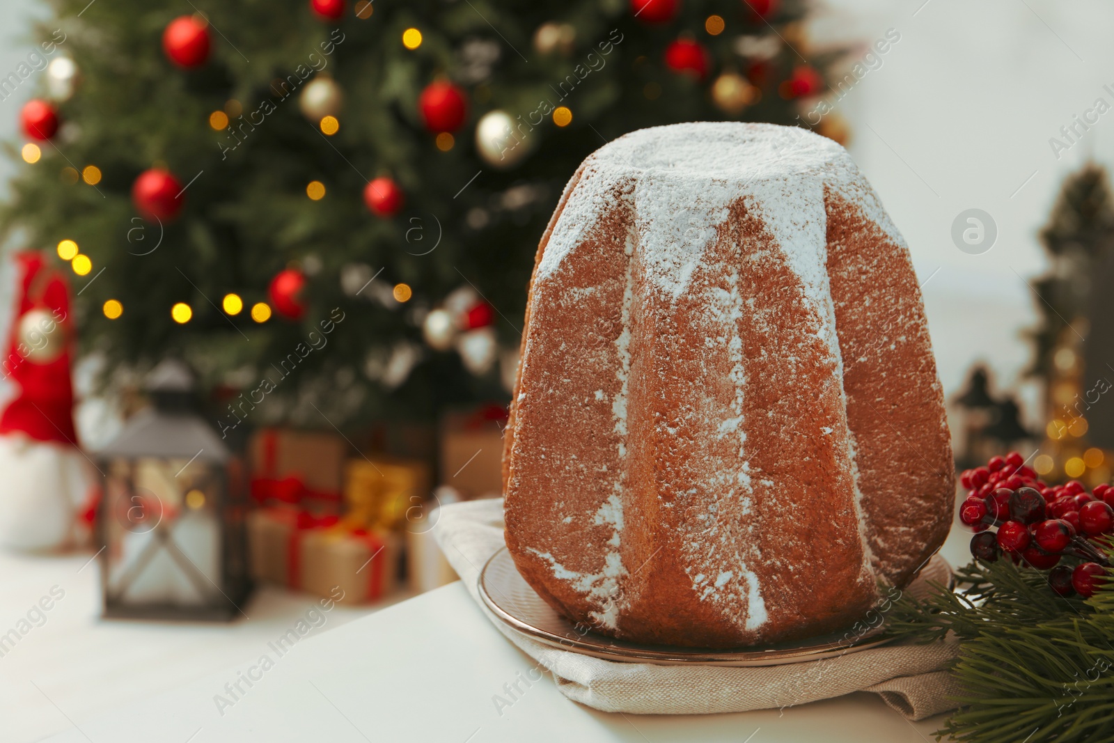 Photo of Traditional Italian pastry. Delicious Pandoro cake decorated with powdered sugar on white table in room, space for text