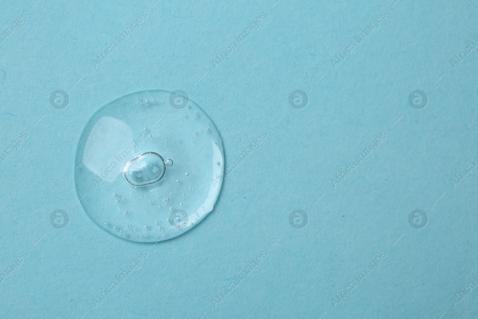 Photo of Sample of cosmetic serum on light blue background, top view. Space for text