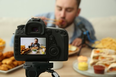 Photo of Food blogger recording eating show against light background, focus on camera screen. Mukbang vlog