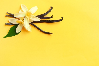 Photo of Flat lay composition with vanilla sticks and flowers on yellow background. Space for text