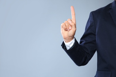 Photo of Businessman pointing on grey background, closeup view of hand with space for text