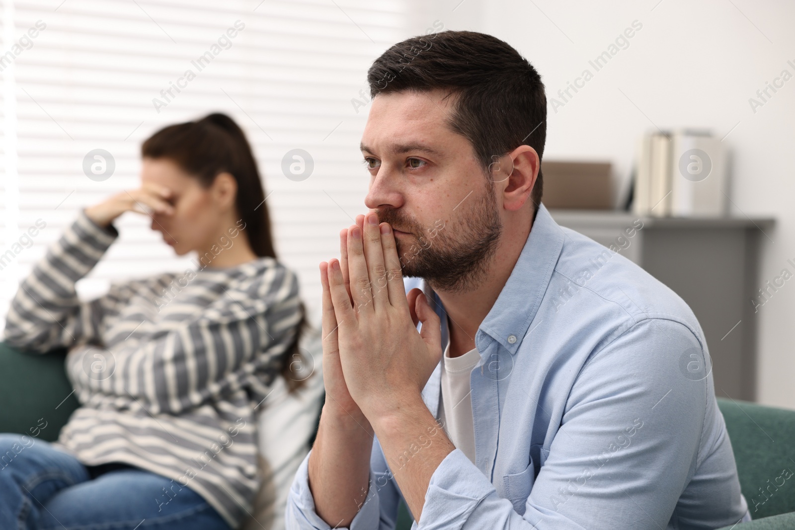 Photo of Offended couple ignoring each other after quarrel indoors, selective focus. Relationship problems