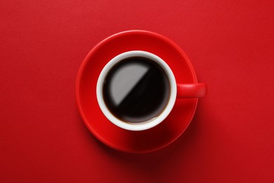 Photo of Cup with aromatic coffee on red background, top view