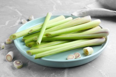 Plate with fresh lemongrass stalks on light grey marble table, closeup