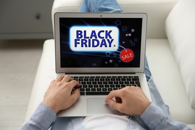 Photo of Man shopping online using laptop on couch at home, closeup. Black Friday Sale