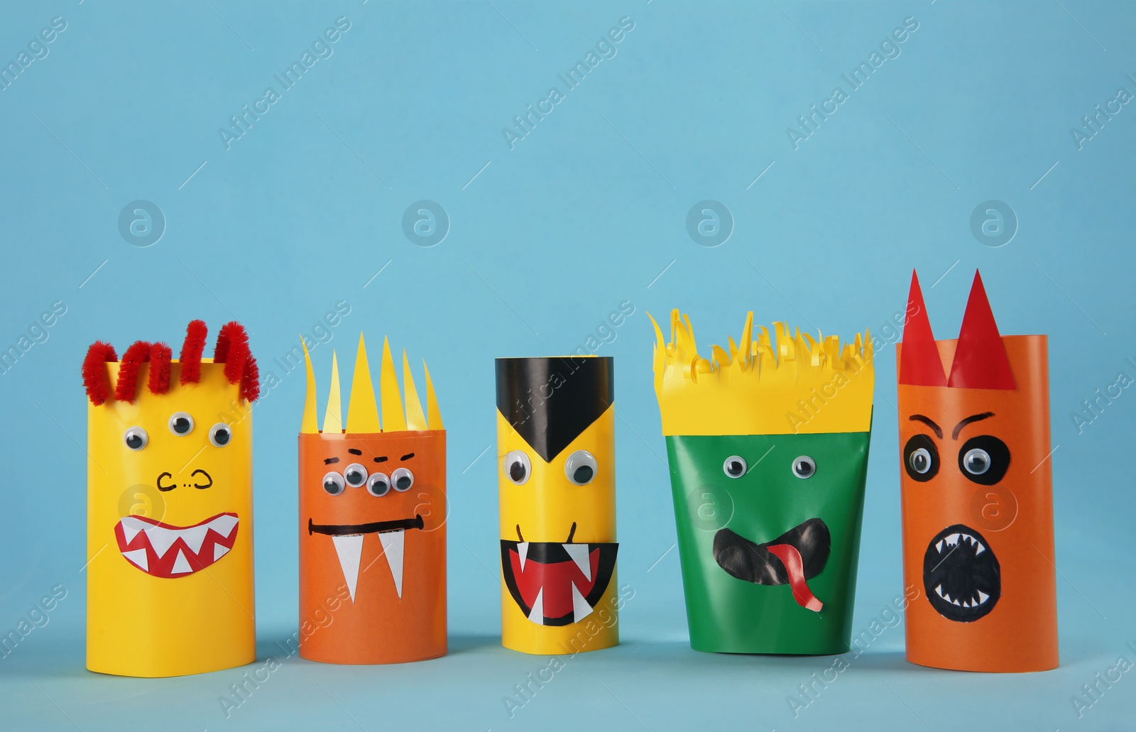 Photo of Funny monsters on light blue background. Halloween decoration