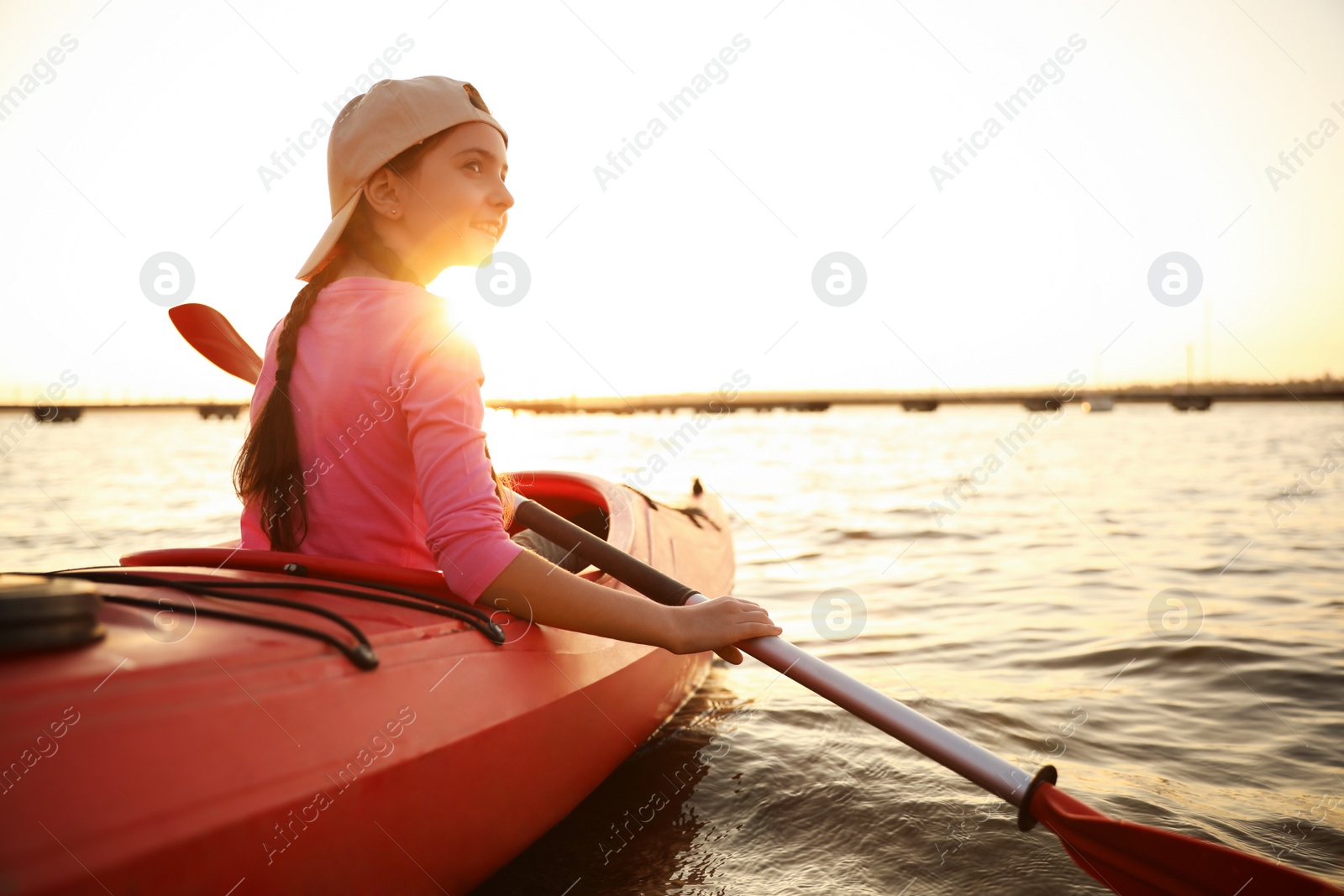 Photo of Happy girl kayaking on river at sunset. Summer camp activity