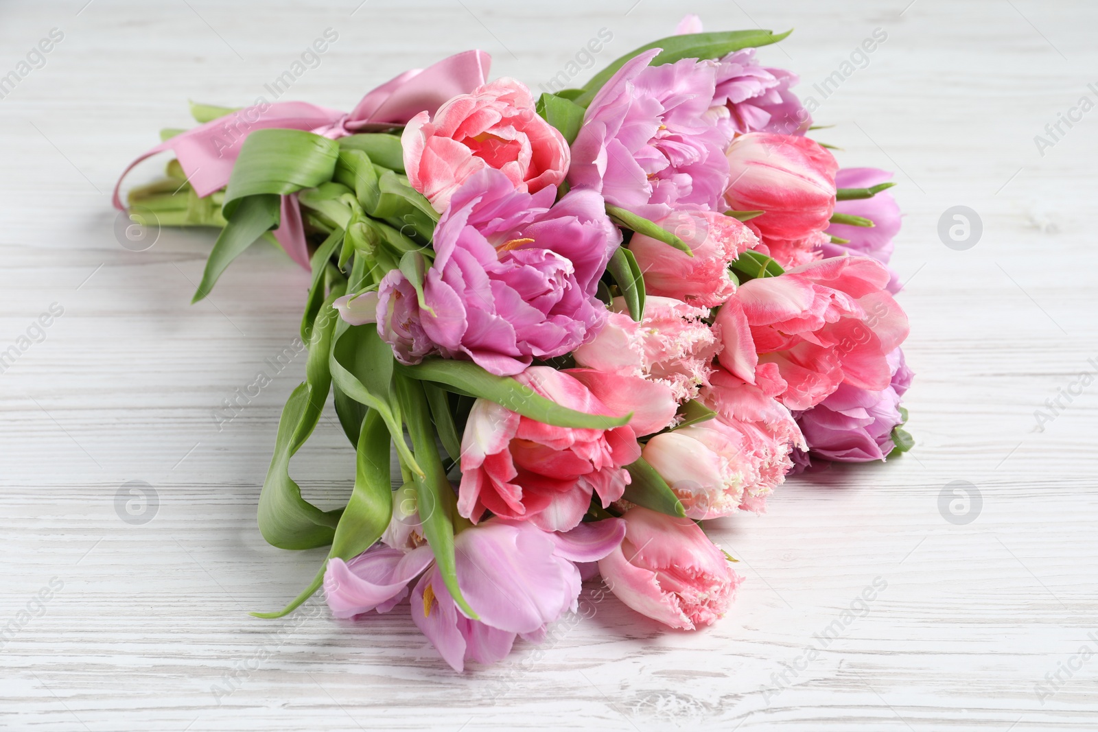 Photo of Beautiful bouquet of colorful tulip flowers on white wooden table