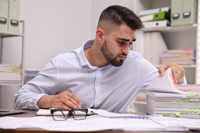 Photo of Overwhelmed man sitting at table in office