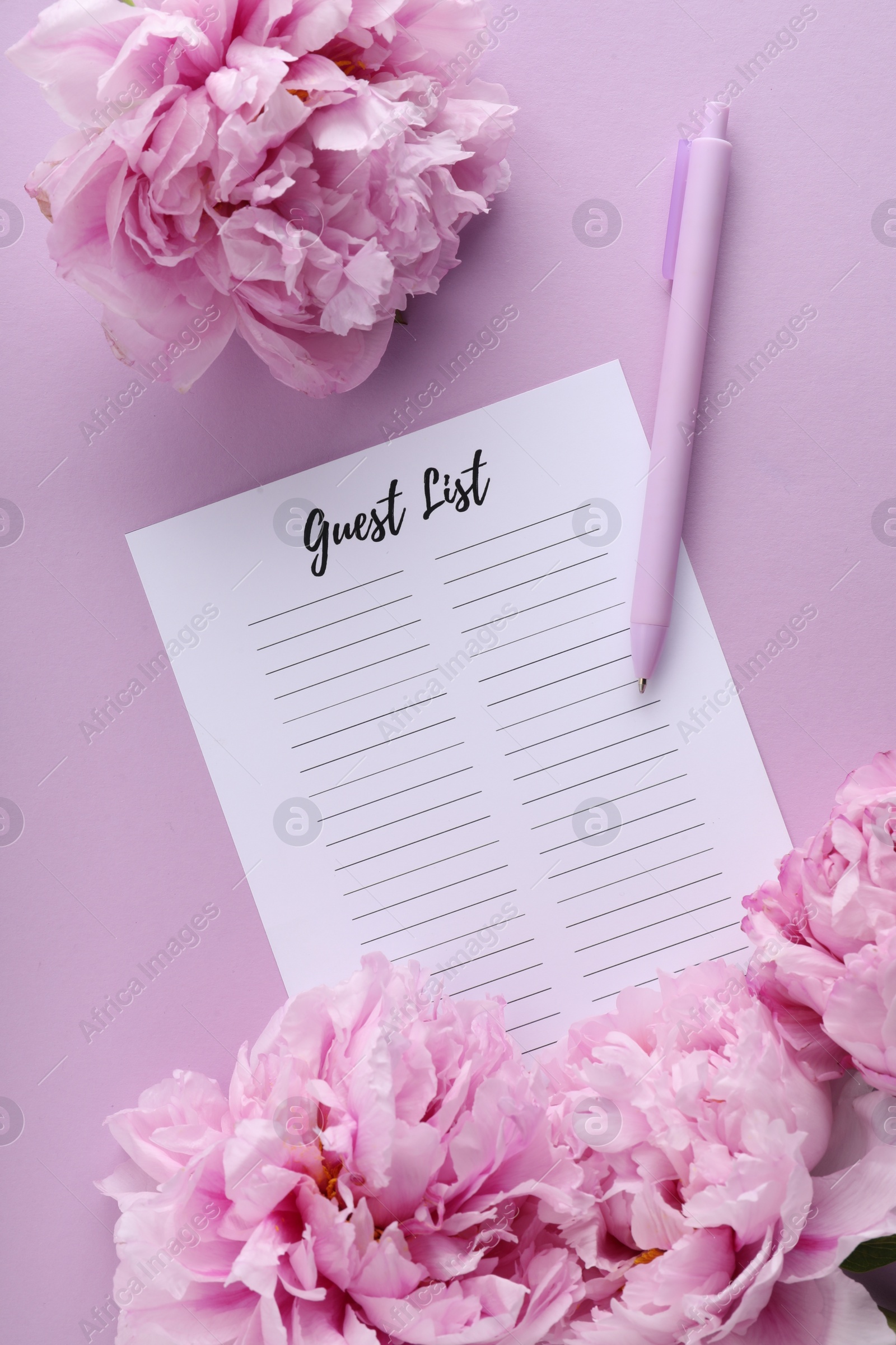 Photo of Guest list, pen and beautiful flowers on violet background, flat lay. Space for text