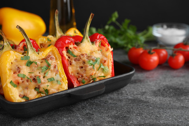 Photo of Tasty stuffed bell peppers in baking pan on grey table, closeup