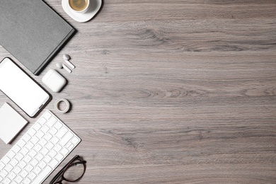 Flat lay composition with computer keyboard and smartphone on wooden table. Space for text