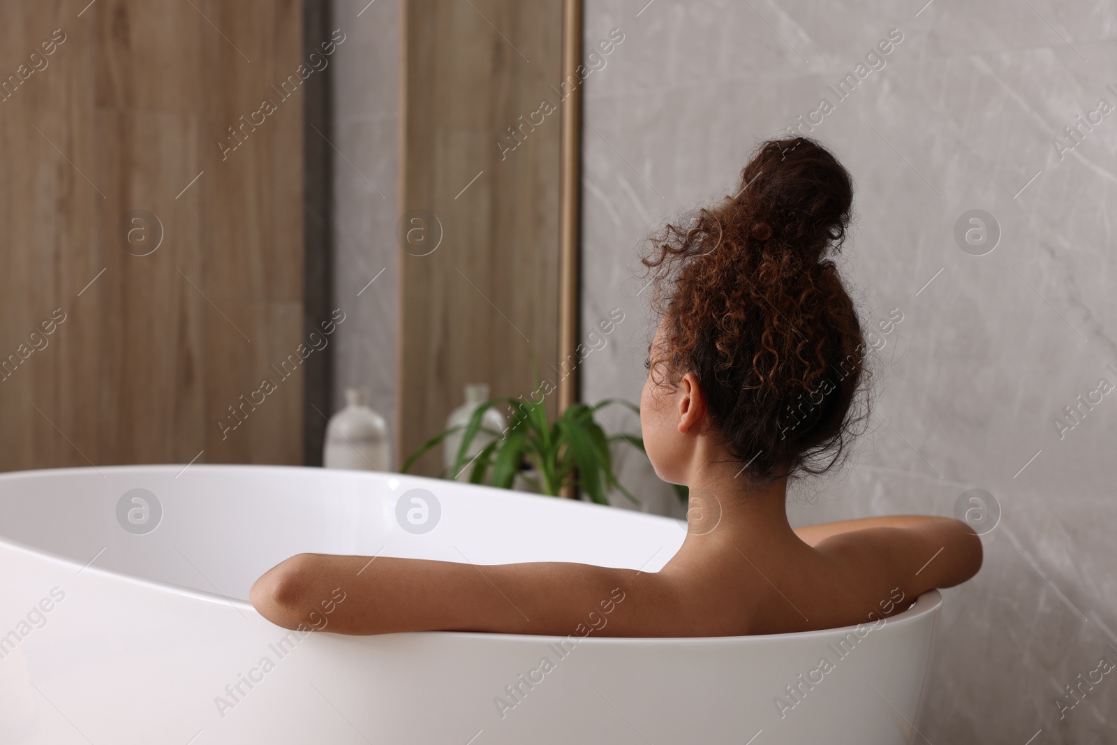 Photo of African American woman taking bath indoors, back view. Space for text