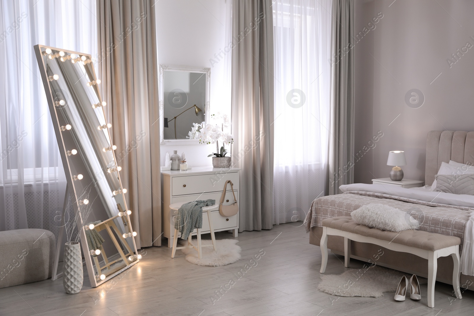 Photo of Large mirror with light bulbs and chest of drawers in bedroom. Interior design