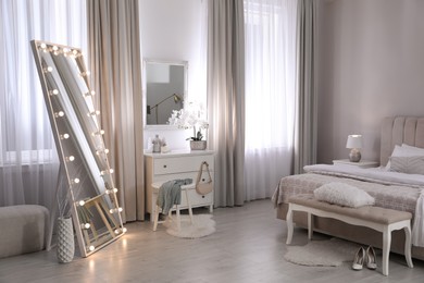 Photo of Large mirror with light bulbs and chest of drawers in bedroom. Interior design