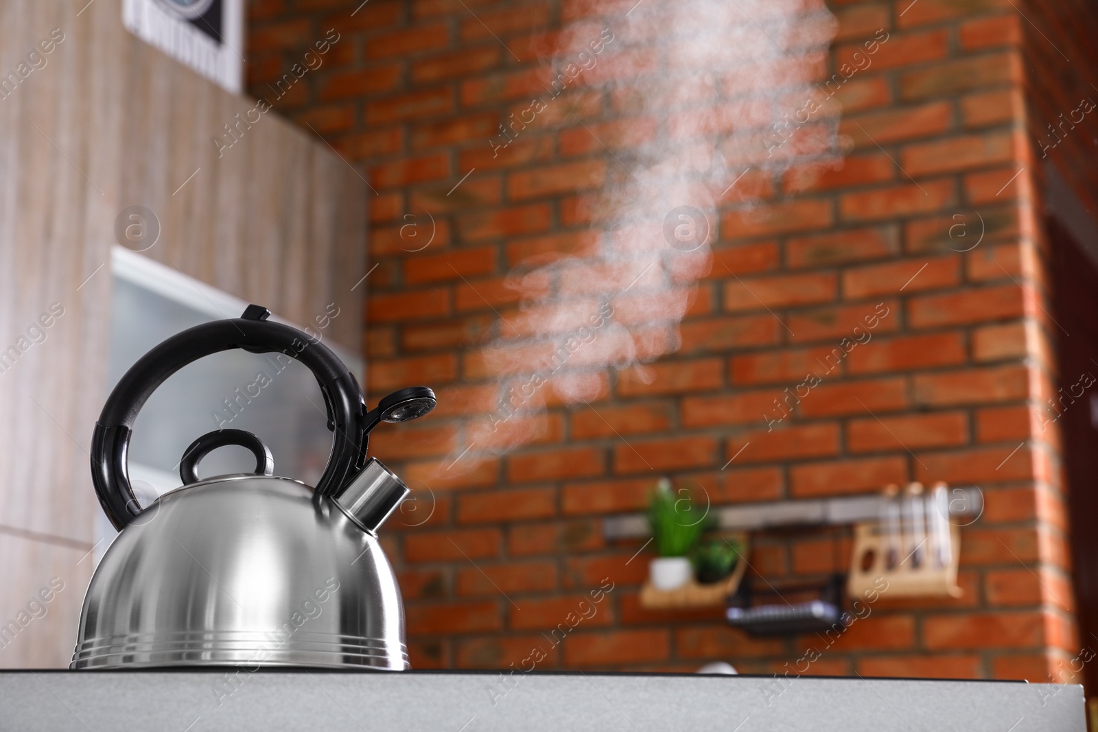 Photo of Modern kettle with whistle on stove in kitchen, space for text