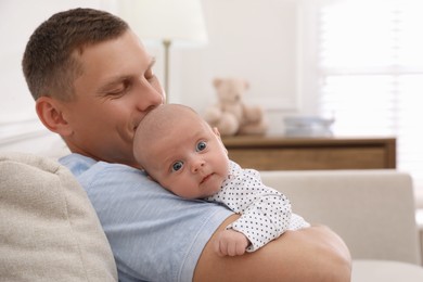 Happy father holding his cute little baby at home, space for text