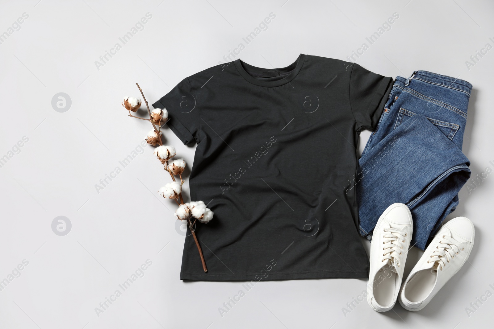 Photo of Stylish t-shirt, jeans and sneakers on light grey background, flat lay