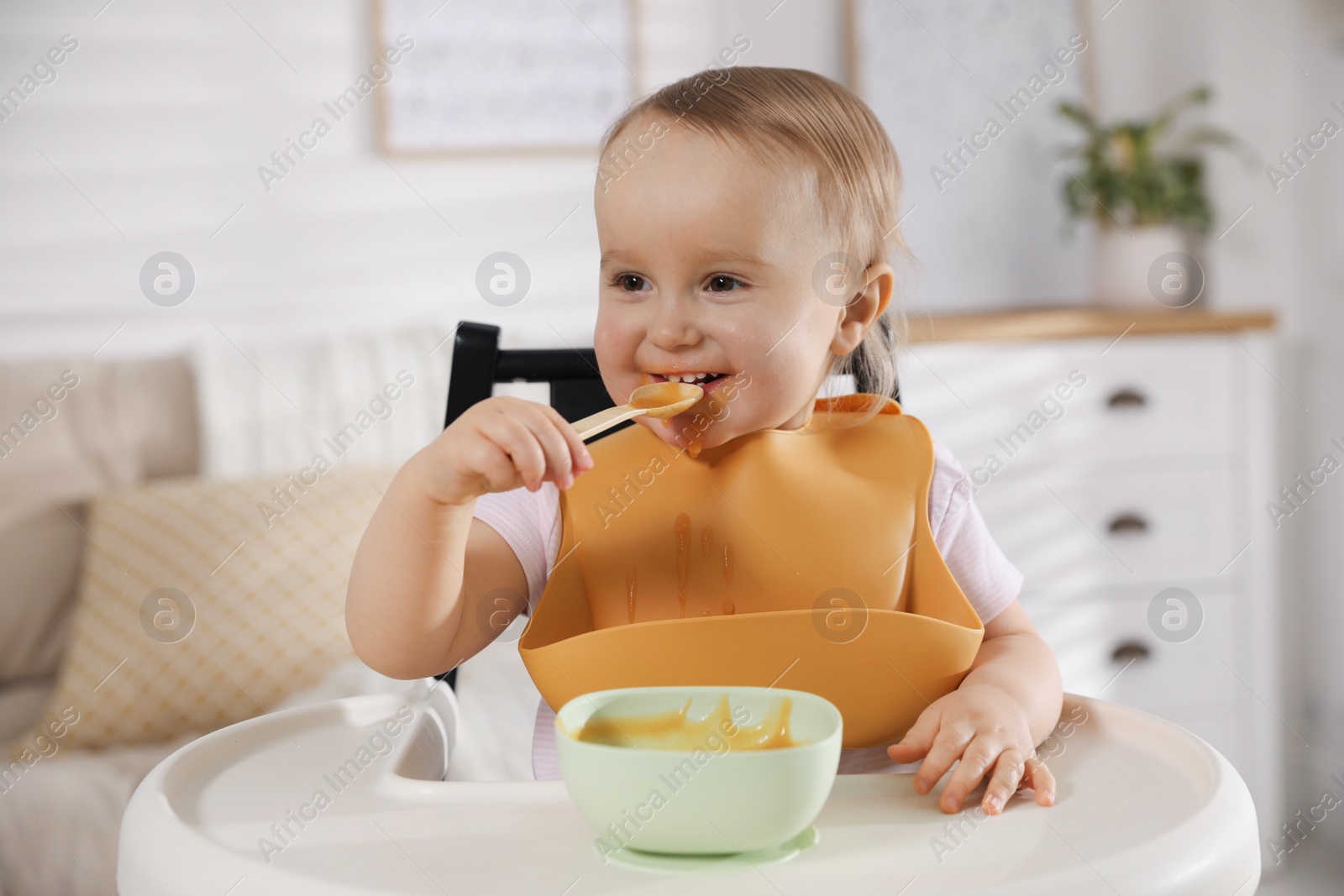 Photo of Cute little baby wearing bib while eating at home