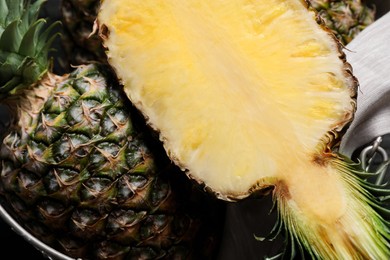 Whole and cut ripe pineapples in metal basket on table, flat lay