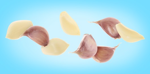 Image of Fresh garlic cloves falling on light blue background, banner design