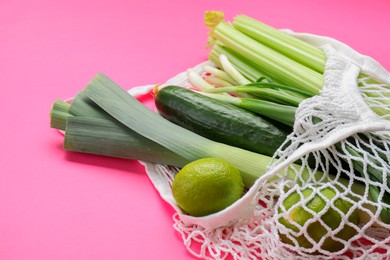 String bag with different vegetables on bright pink background, closeup