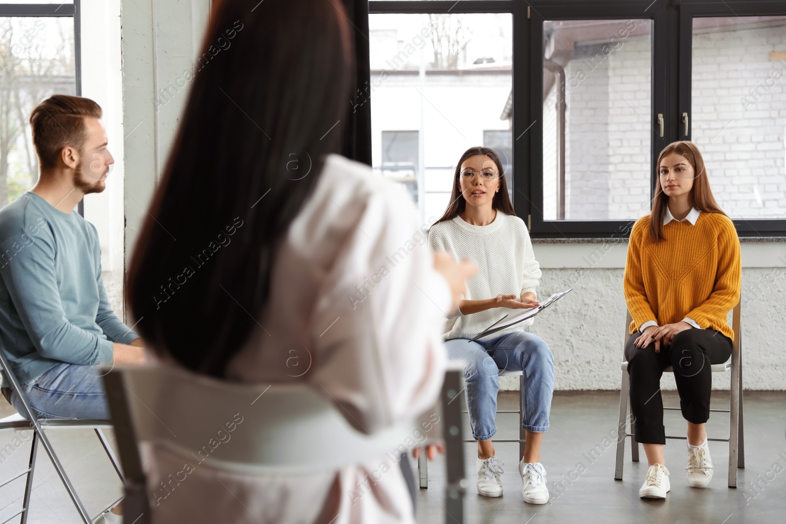 Photo of Psychotherapist working with patients in group therapy session indoors