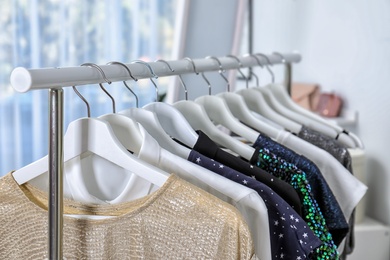 Stylish clothes hanging on wardrobe rack indoors, closeup