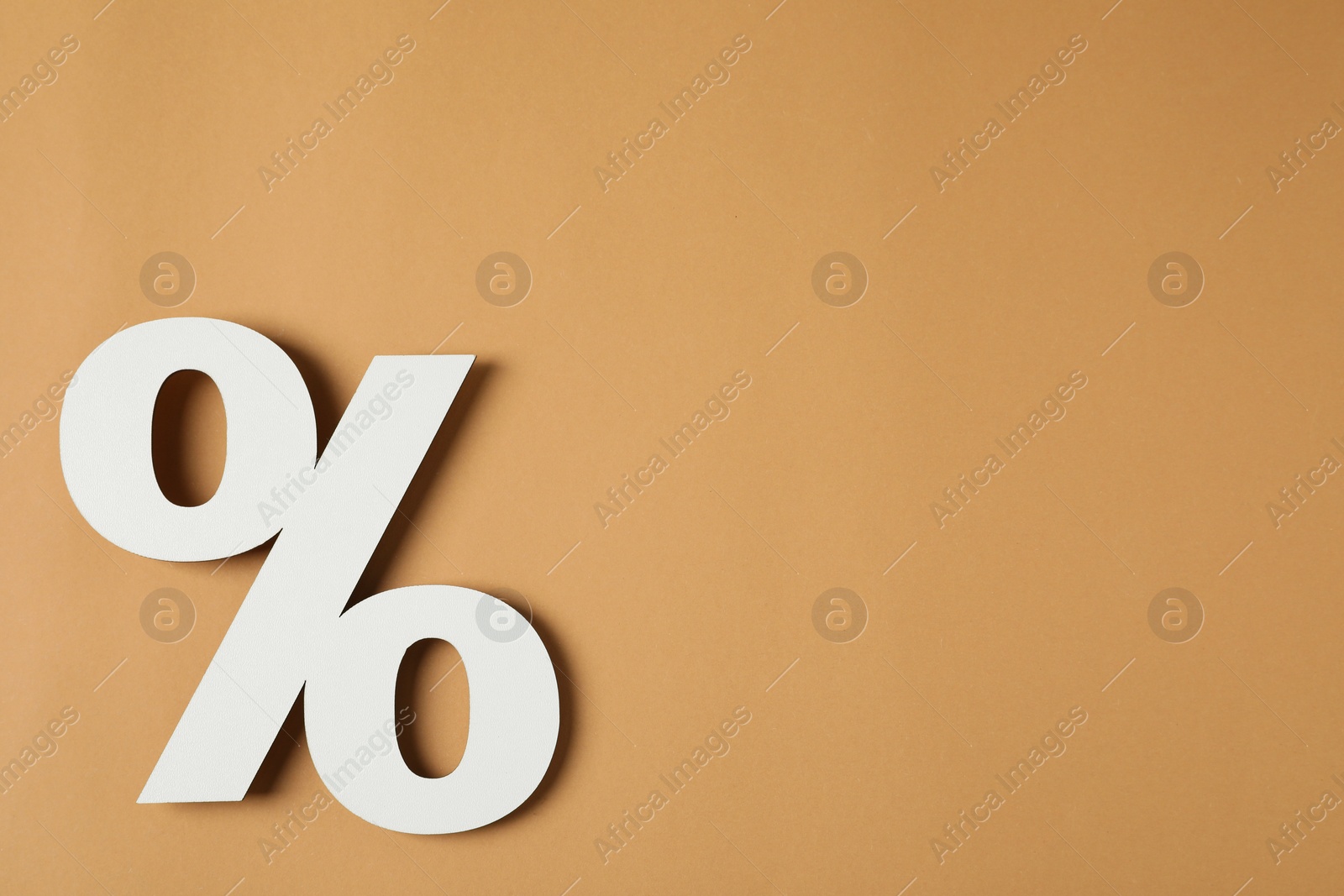 Photo of White percent sign on light brown background, top view. Space for text