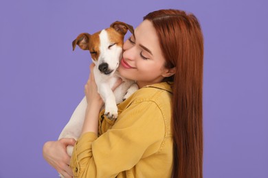 Photo of Woman hugging her cute Jack Russell Terrier dog on violet background