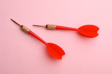 Red dart arrows on pink background, flat lay