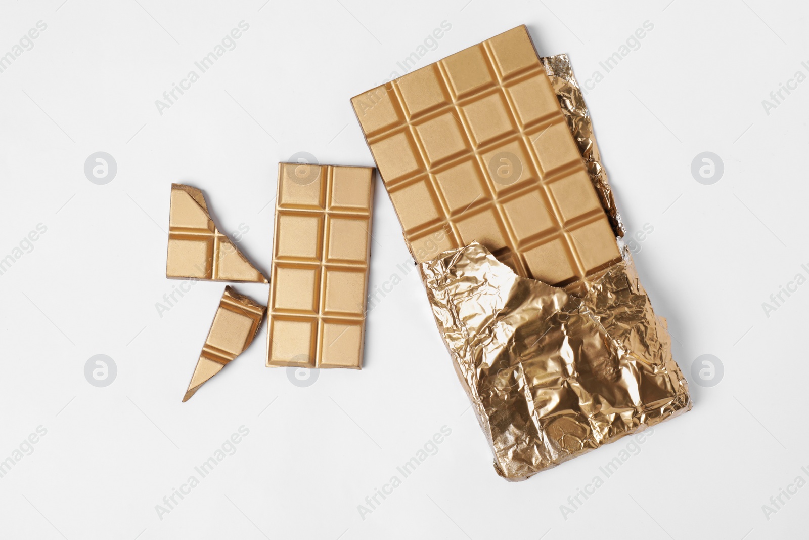 Photo of Shiny golden chocolate bar with foil on white background, top view