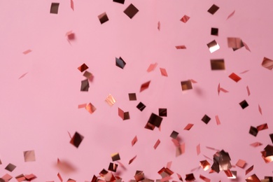 Photo of Shiny confetti falling down on pink background