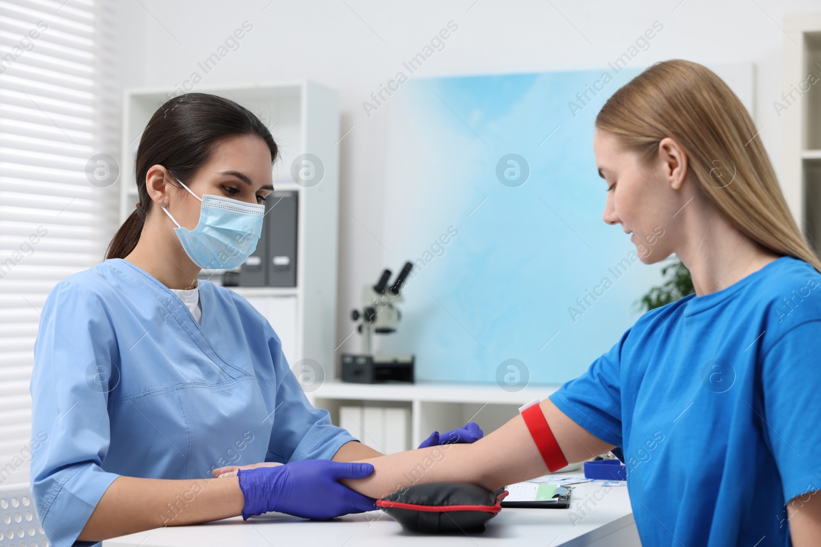 Photo of Laboratory testing. Doctor taking blood sample from patient at white table in hospital