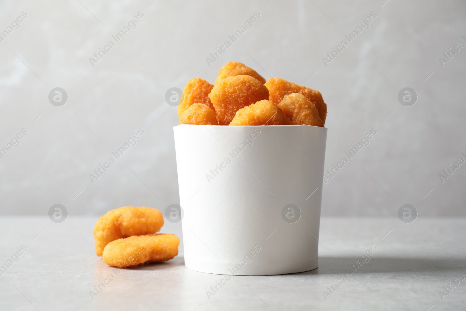 Photo of Delicious fried chicken nuggets on light grey table