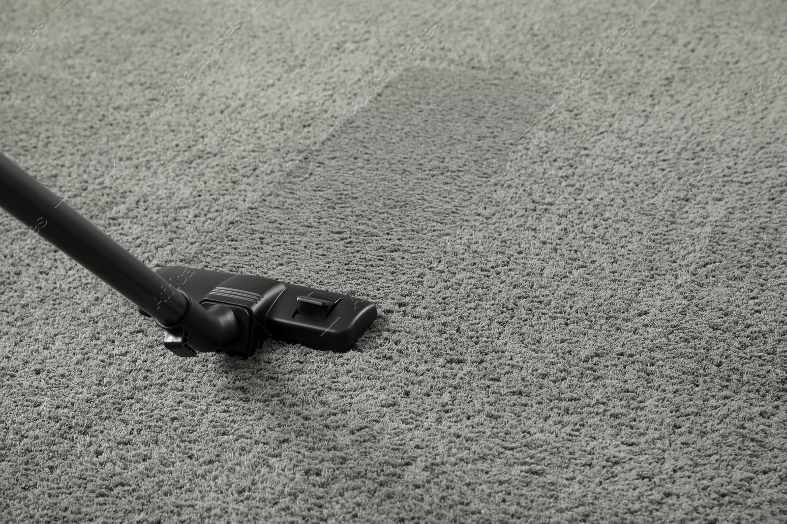 Photo of Removing dirt from grey carpet with modern vacuum cleaner. Space for text