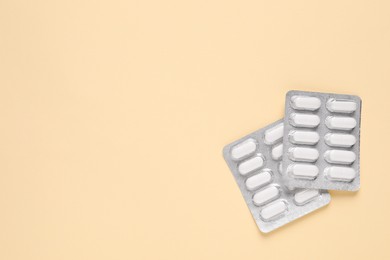 Photo of Pills in blisters on beige background, top view. Space for text