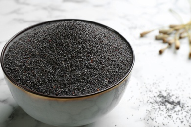 Poppy seeds in bowl on white marble table