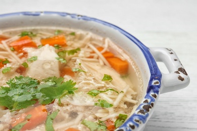 Photo of Dish with fresh homemade chicken soup on wooden table, closeup