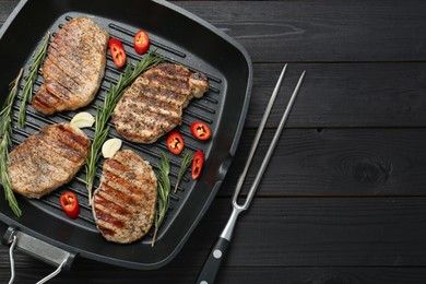 Delicious pork steaks served on black wooden table, top view. Space for text