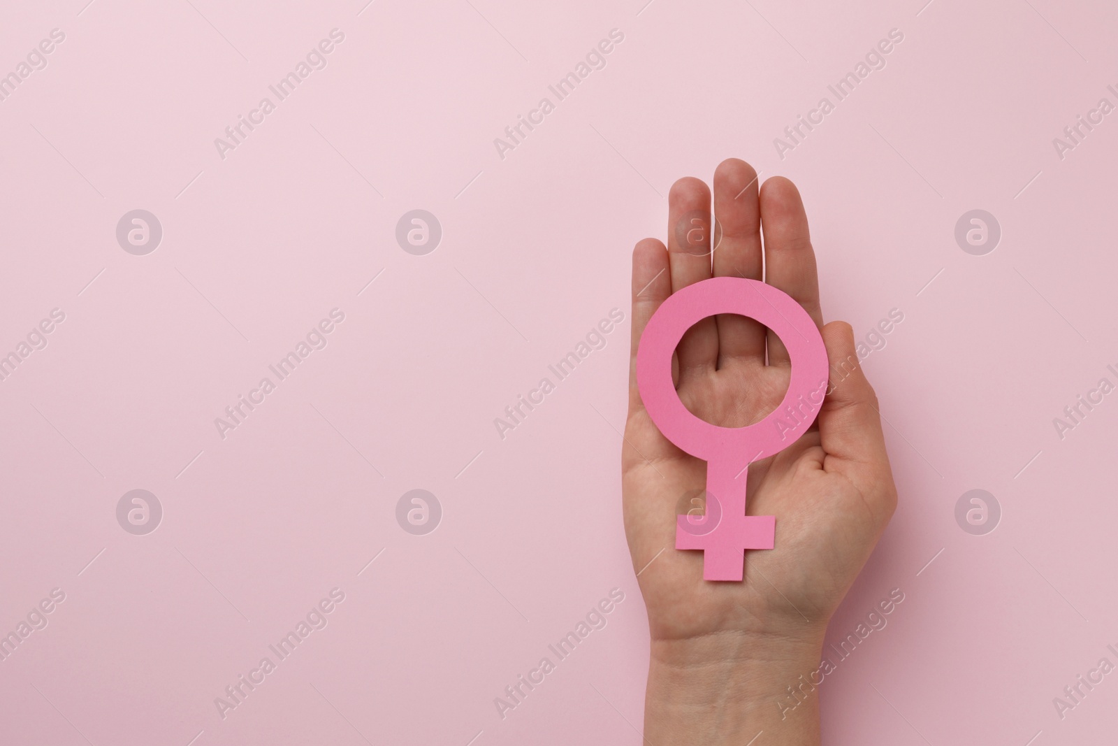 Photo of Woman holding female gender sign on pink background, top view. Space for text