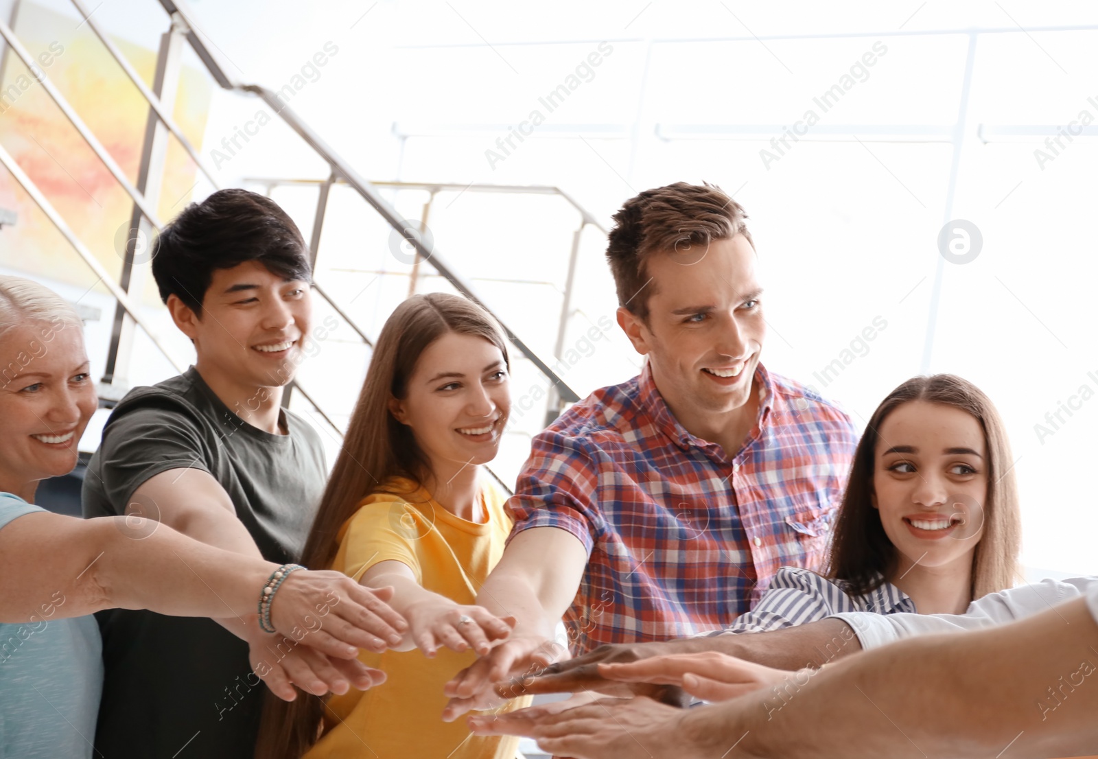 Photo of People putting hands together indoors. Unity concept