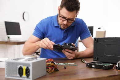 Photo of Male technician repairing computer at table indoors