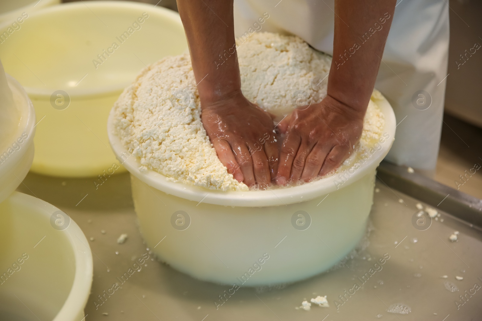 Photo of Worker pressing curd into mould at cheese factory, closeup