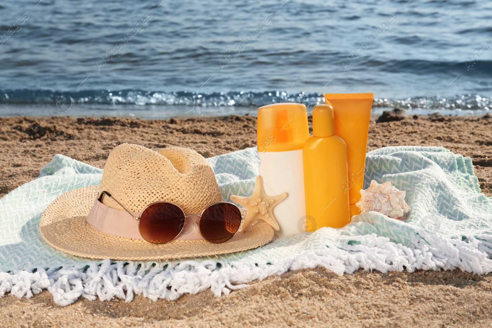 Photo of Sun protection products and beach accessories on blanket near sea