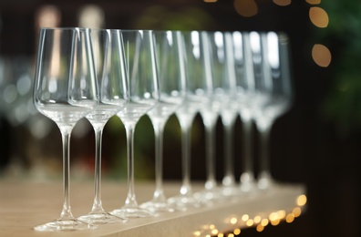 Photo of Set of empty wine glasses on grey table against blurred background