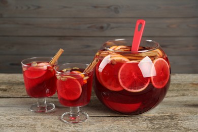 Photo of Glasses and bowl with aromatic punch drink on wooden table