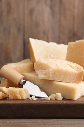 Delicious parmesan cheese with knife on wooden table